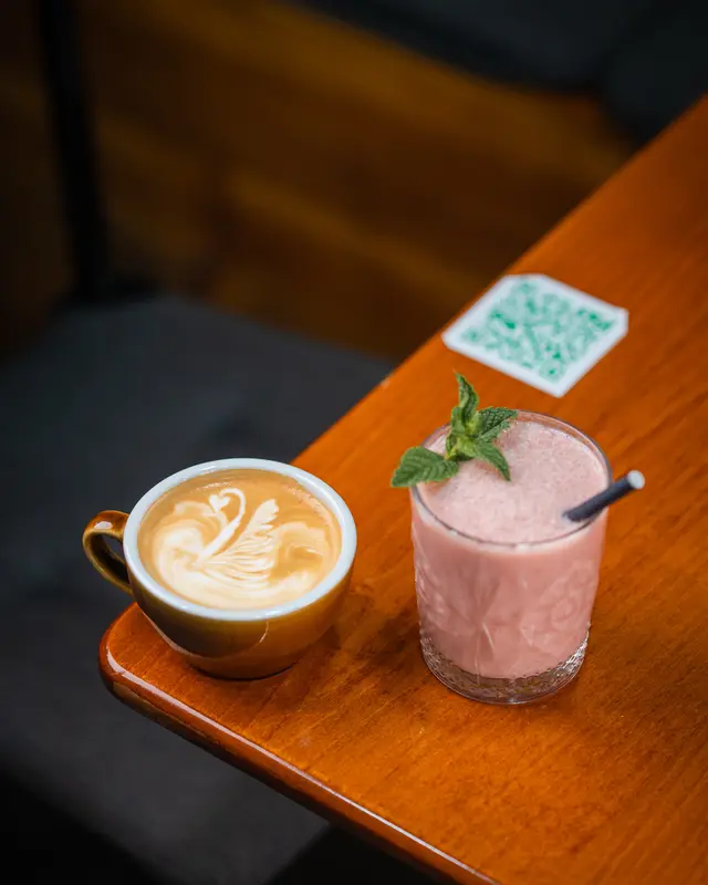 A flat white and a smoothie on a wooden table