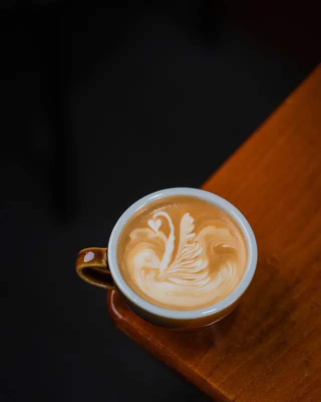 A latte with swan latte art on a wooden table